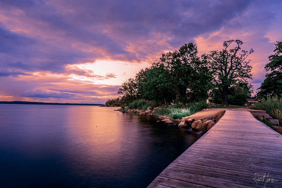 Brygga vid stilla sjö i solnedgång