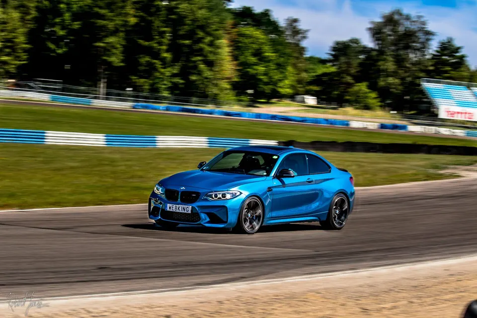 Blå BMW M2 i full fart genom en kurva på Mantorp Park